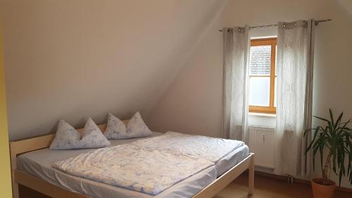 a bedroom with a bed with pillows and a window at Ferienwohnung Abel in Heideck