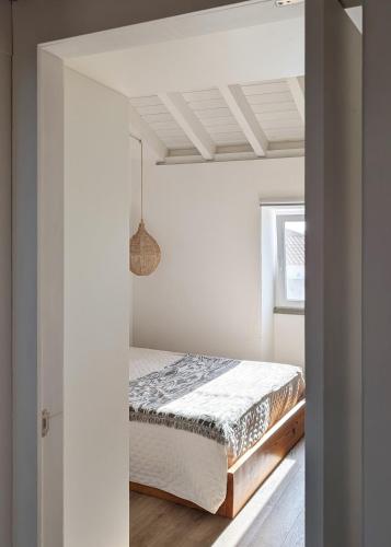 a bedroom with a bed in a white room at OKTO Beach House in Praia do Almoxarife