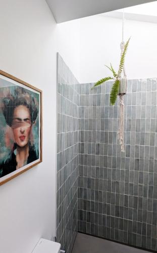 a bathroom with a painting of a woman on the wall at OKTO Beach House in Praia do Almoxarife