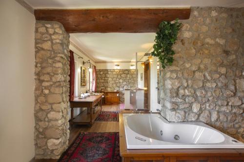 a bathroom with a tub and a stone wall at Villa Terrarossa with Pool in the Vineyard in Mezzane di Sotto