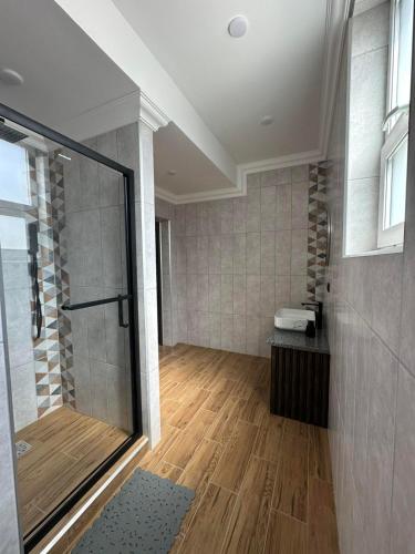 a bathroom with a shower and a wooden floor at Sting Hotel & Apartments in Velikaya Dobronʼ