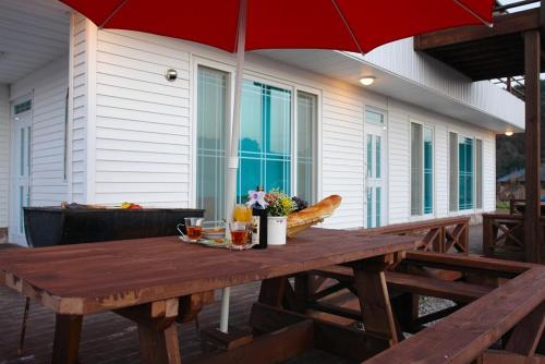 a wooden picnic table with an umbrella on a patio at Buan Solseom House Pension in Buan