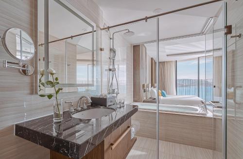 a bathroom with a sink and a glass shower at The Zenix Hotel Seaview in Nha Trang