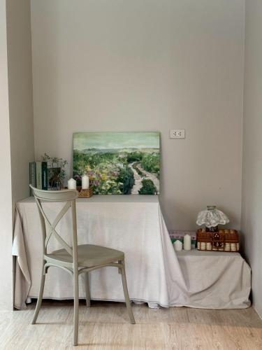 a table with a chair and a painting on the wall at silverpine khao kho in Phetchabun