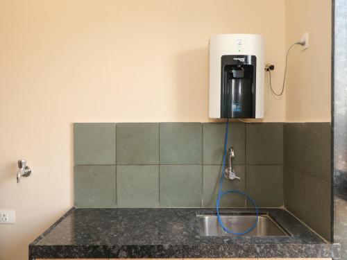 a sink in a bathroom with a water heater on the wall at Hotel Tattva Suites NIBM, next to Corinthians Club in Pune