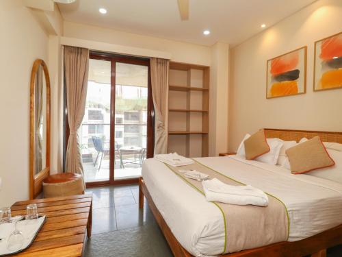 a bedroom with a bed and a bathroom with a balcony at Hotel Tattva Suites NIBM, next to Corinthians Club in Pune
