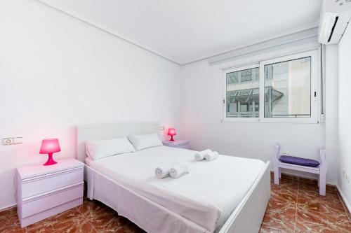 a white bedroom with a white bed and a window at Sunrise Arts 1 in Torrevieja
