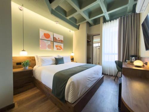 a bedroom with a large bed and a desk at Urbit Garden Hotel in Medellín