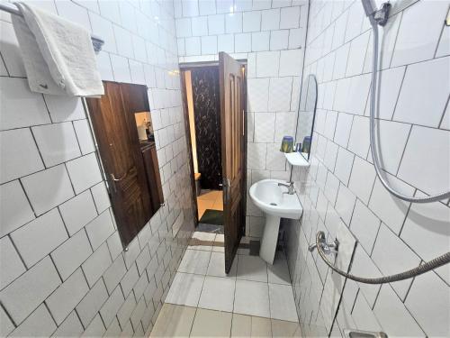 a white tiled bathroom with a sink and a mirror at The Yafé Bastos 6 in Yaoundé