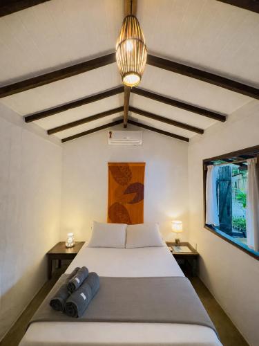 a bedroom with a bed with two tables and a lamp at Pousada Aratu - Vila de Caraíva - A apenas 100 metros da travessia de canoa in Caraíva