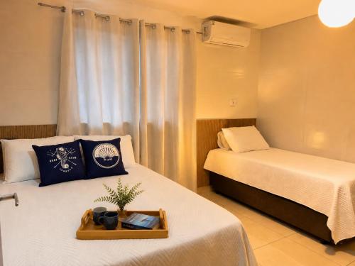 a bedroom with two beds and a tray with a plant on it at Ocean Residence - Aptos Pé na Areia Ponta do Papagaio in Palhoça