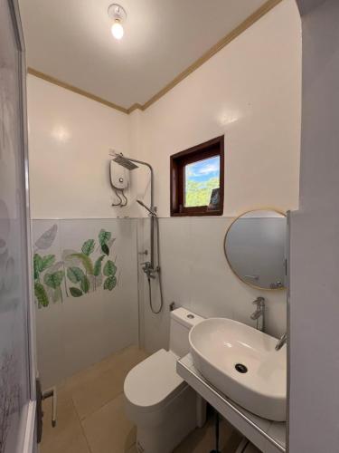 a bathroom with a toilet and a sink and a mirror at A-rena Homestay in General Luna