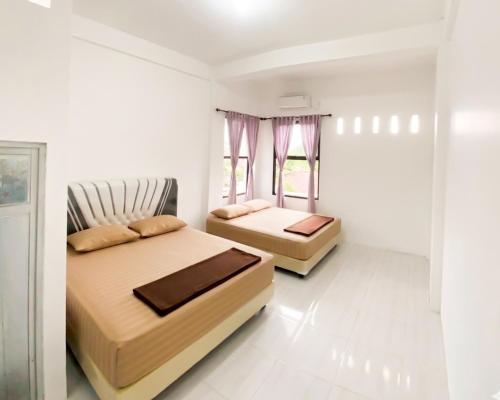 two beds in a room with white walls at Lansogo Homestay in Painan