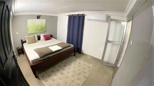 a bedroom with a bed with blue curtains and a window at The Yafé Bastos 9 in Yaoundé