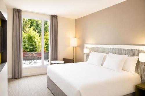 a hotel room with a bed and a balcony at Best Western Plus Paris Meudon Ermitage in Meudon