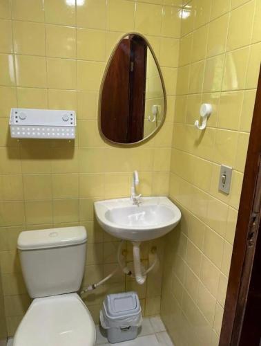 a bathroom with a toilet and a sink and a mirror at Quarto Meudon in Teresópolis