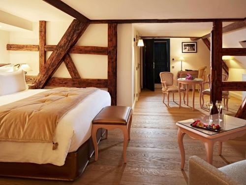 a hotel room with a bed and a table and chairs at Cour du Corbeau Hotel Strasbourg - MGallery Collection in Strasbourg