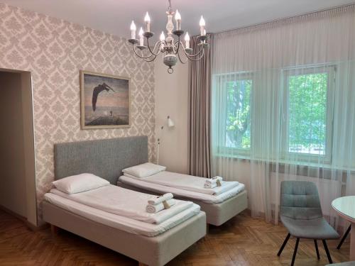 a room with two beds and a table and a chandelier at KUBU namai in Klaipėda