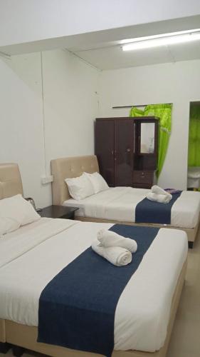a room with three beds and a tv in it at Cozy Highland in Tanah Rata