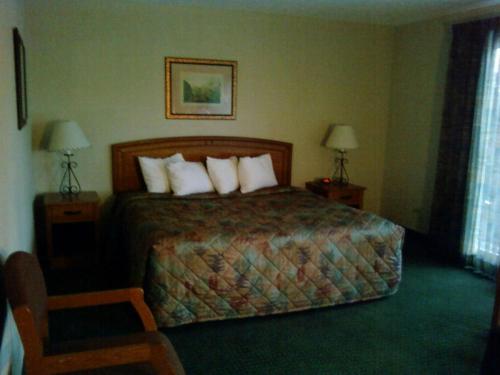 a hotel room with a bed with pillows and two lamps at Will Rogers Inn in Claremore