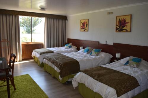 a hotel room with three beds and a window at Complejo Pehuen Lago Lanalhue in Cañete