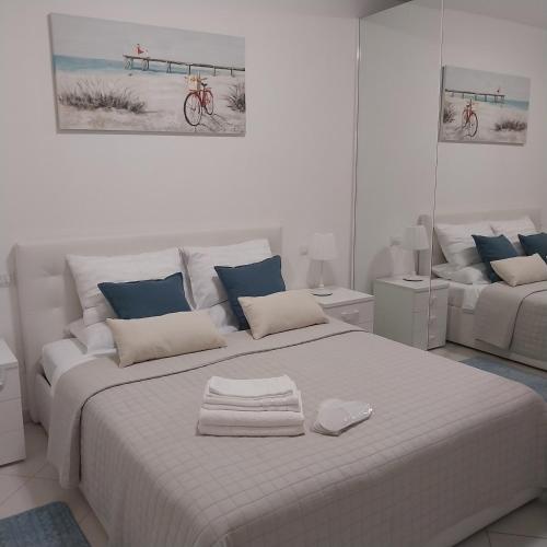 a white bedroom with a large white bed with blue pillows at B&B El Dorado in Lido di Pomposa