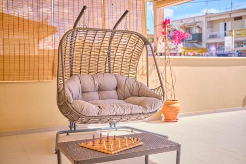 a wicker rocking chair with a table with a chessboard at Irene Luxury Suite Roda in Roda