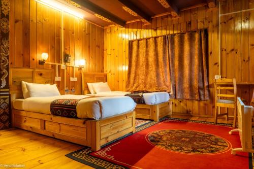 two beds in a room with wooden walls at Phuntsho Guest House in Jakar
