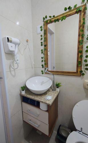 a bathroom with a sink and a mirror and a toilet at Apartamento Canasvieiras in Florianópolis