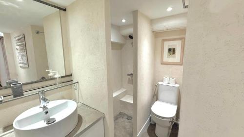 a white bathroom with a sink and a toilet at Le Refuge in Denicé