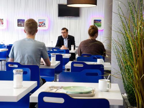 a group of people sitting at tables in a restaurant at Ibis budget Koeln Messe in Cologne