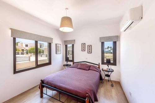 a bedroom with a bed and two windows at Villa Sea Side in Polis Chrysochous