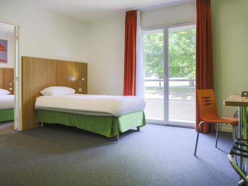 a hotel room with a bed and a large window at ibis Styles Bourbon Lancy in Bourbon-Lancy