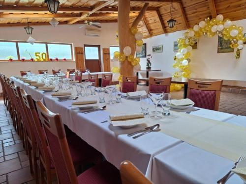 a long table in a room with white tables and chairs at Penzión U Tonky in Tomek