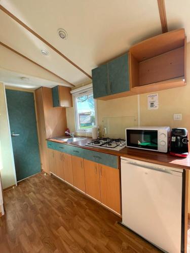 a kitchen with a microwave and a stove top oven at Ruben Bungalow in Bourbourg