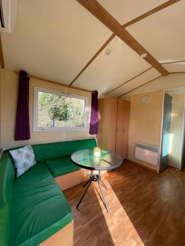 a living room with a green couch and a table at Ruben Bungalow in Bourbourg