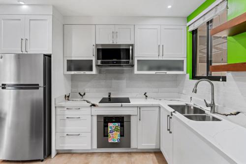 a kitchen with white cabinets and a stainless steel refrigerator at Colorful & Private 2-Bedroom Condo Just a Short Walk from the Beach in Coco