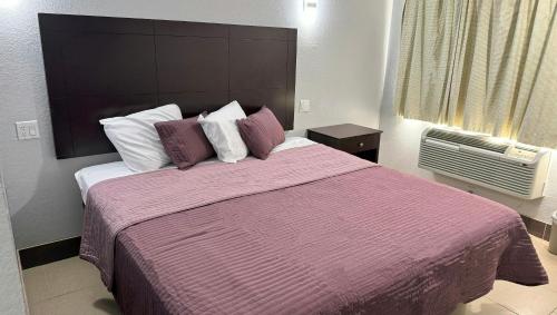 a bedroom with a large bed with purple sheets and pillows at Xpress Inn & Extended Stays in Marshall