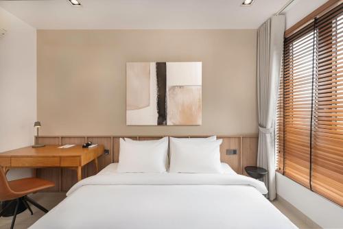 a bedroom with a white bed and a desk at Velea Serviced Apartments & Suites in Siem Reap