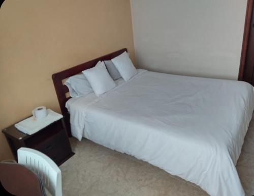a bedroom with a bed and a nightstand with a white bedspread at Hotel Surandino Fátima in Pasto