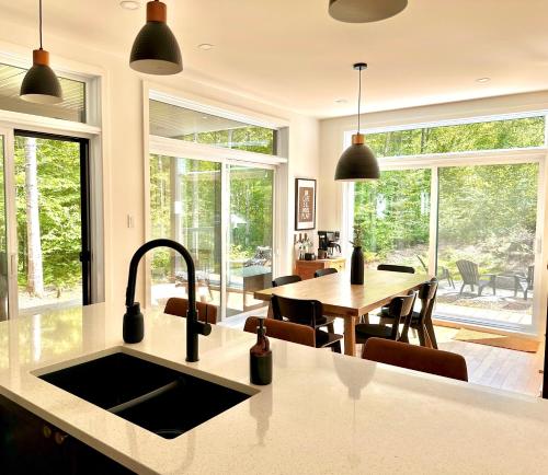 a kitchen with a sink and a table with chairs at Chalet Le St-Ray in Saint-Raymond