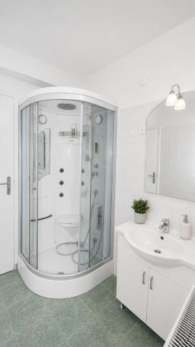 a white bathroom with a shower and a sink at Szabó Tanya Nyim in Nyim