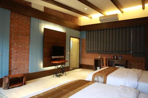 a bedroom with two beds and a flat screen tv at Old House Homestay in Sanxing