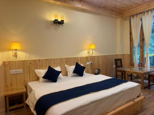 a bedroom with a large bed with blue and white pillows at The Zoland in Jibhi