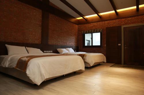 a bedroom with two beds and a brick wall at Old House Homestay in Sanxing