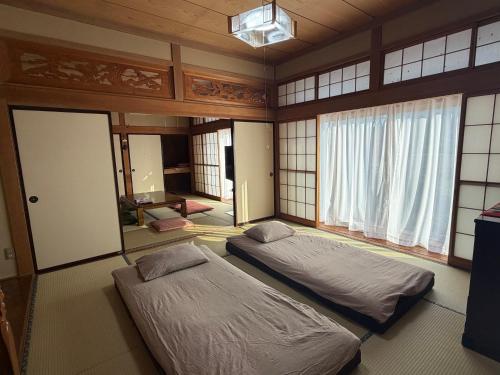 two beds sitting in a room with windows at 民泊ごとう in Kitakami