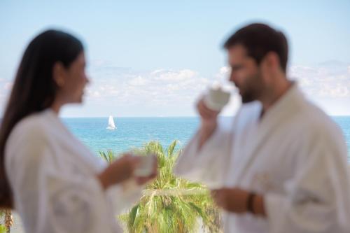 a man and a woman drinking coffee in front of the ocean at Dreams Aventuras Riviera Maya - All Inclusive in Puerto Aventuras