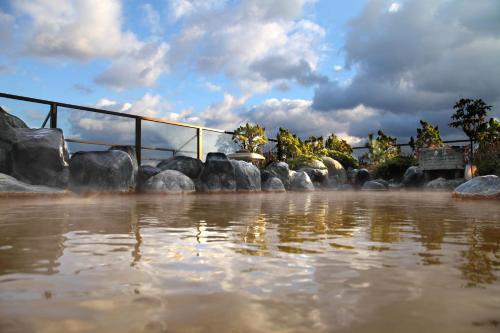 a body of water with rocks and a fence at Heiseikan Kaiyotei in Hakodate