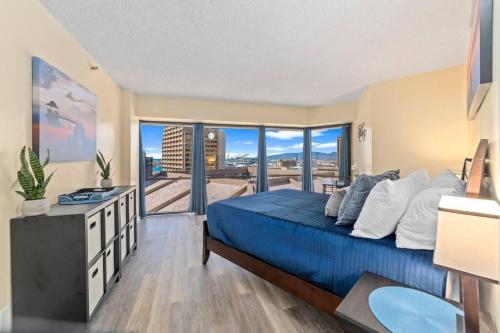 a bedroom with a blue bed and a large window at Executive Center 1604 in Honolulu