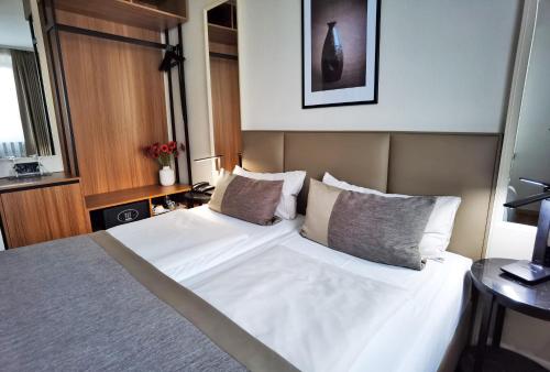 a bedroom with a bed with white sheets and pillows at Hotel Italia in Munich